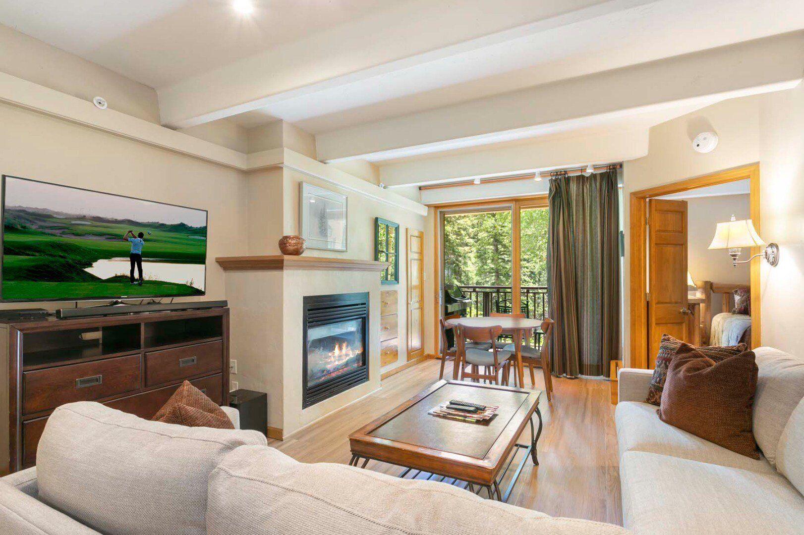 A spacious living room with a fireplace, a television, and a dining area with a view of the outdoors.