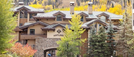 A lodge with a stone facade, multiple chimneys, and a sign reading 'ANTLER'.