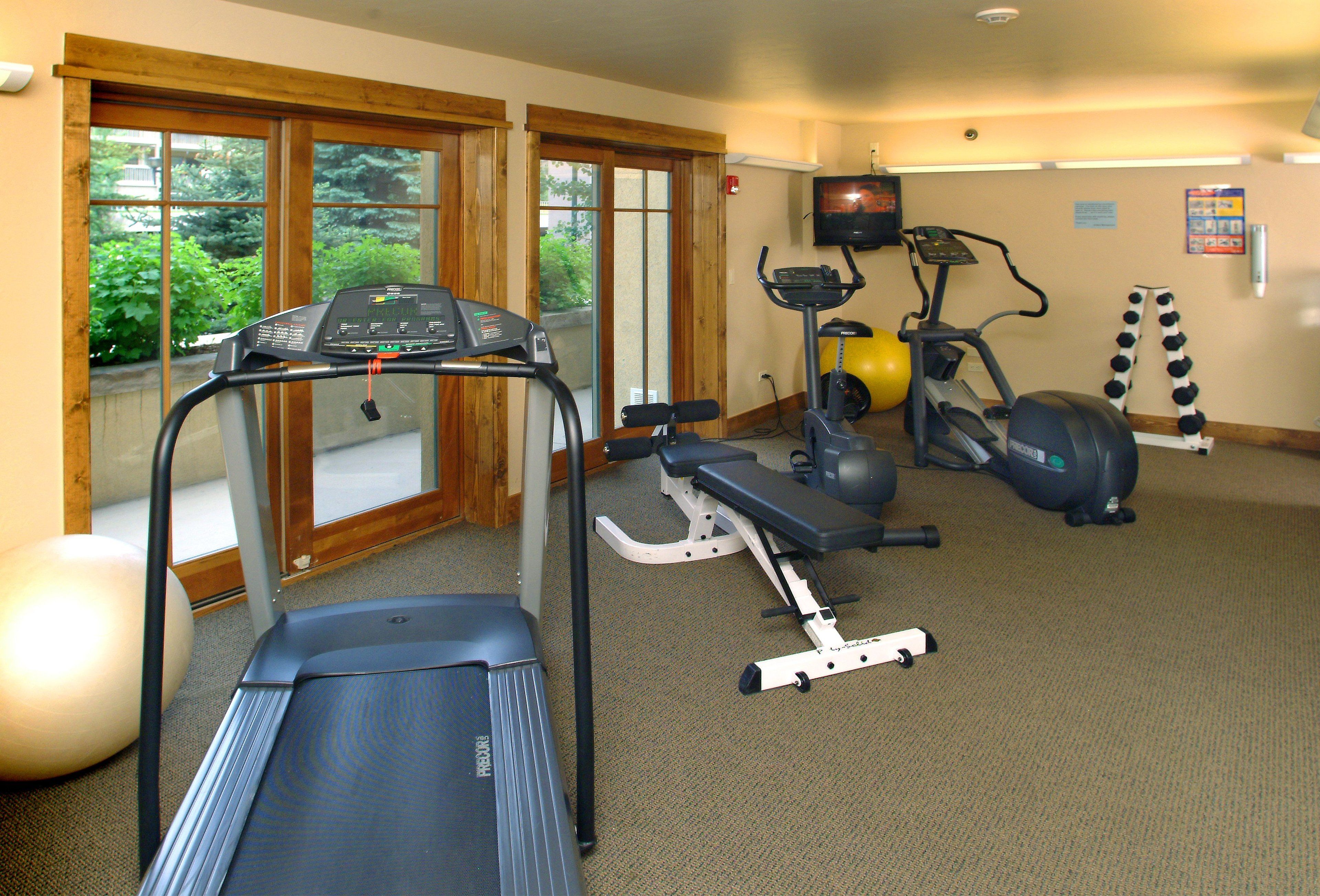 Ein Fitnessraum mit Laufbändern, Crosstrainern und Gymbällen.