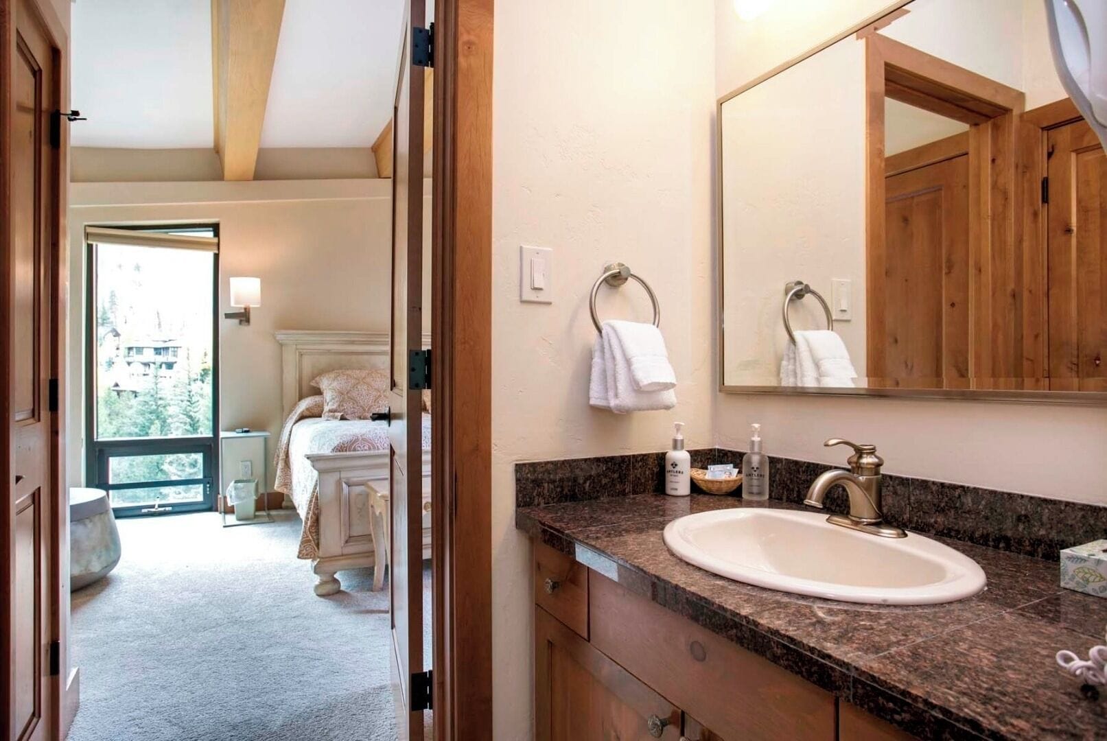 Un baño con un espejo grande, un lavabo y un perchero para toallas.