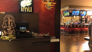 A reception area with a digital display, a statue, and a red mosaic wall.