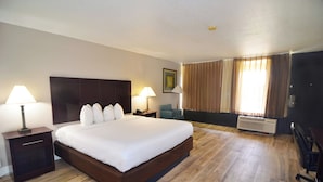A hotel room with a large bed, two bedside tables with lamps, a desk, a chair, and a window with curtains. - Hotel Monreale Inn & Studios I-Drive Icon Park Orlando (Orlando)