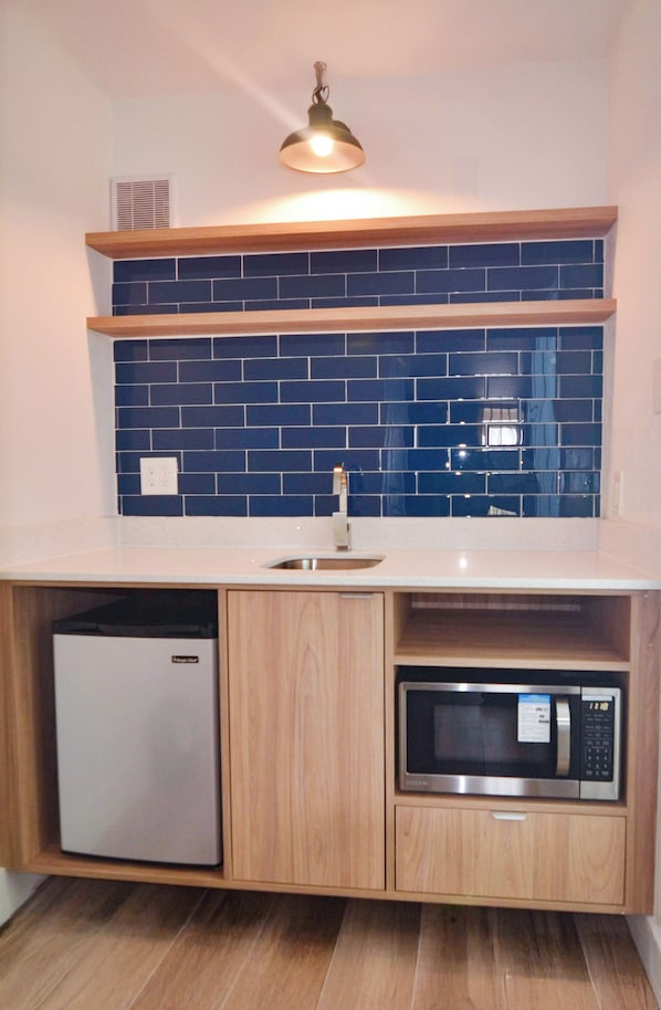 A compact kitchen with a dishwasher, microwave, and a sink.