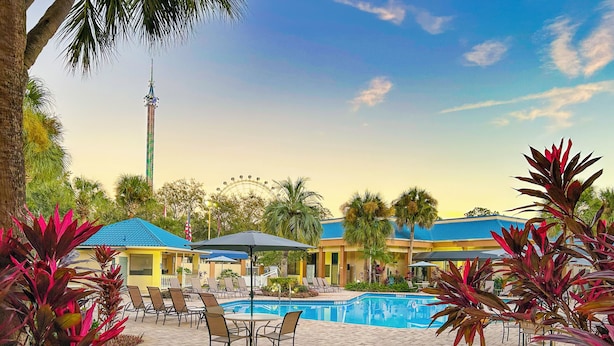 A pool area with lounge chairs and a Ferris wheel in the background. - Hotel Monreale Inn & Studios I-Drive Icon Park Orlando (Orlando)