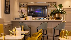 A bar area with a television, bar stools, and a potted plant. - Hotel Park Lane Paris (Paris)
