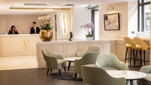 A hotel reception area with a reception desk, seating area, and a large vase of flowers. - Hotel Park Lane Paris (Paris)