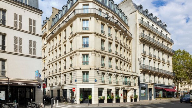 A corner building with multiple stories, balconies, and a sign for a restaurant. - Hotel Park Lane Paris (Paris)