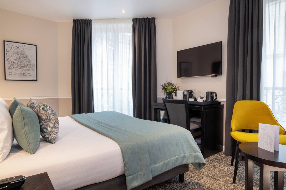 A hotel room with a bed, a desk, a chair, and a TV.