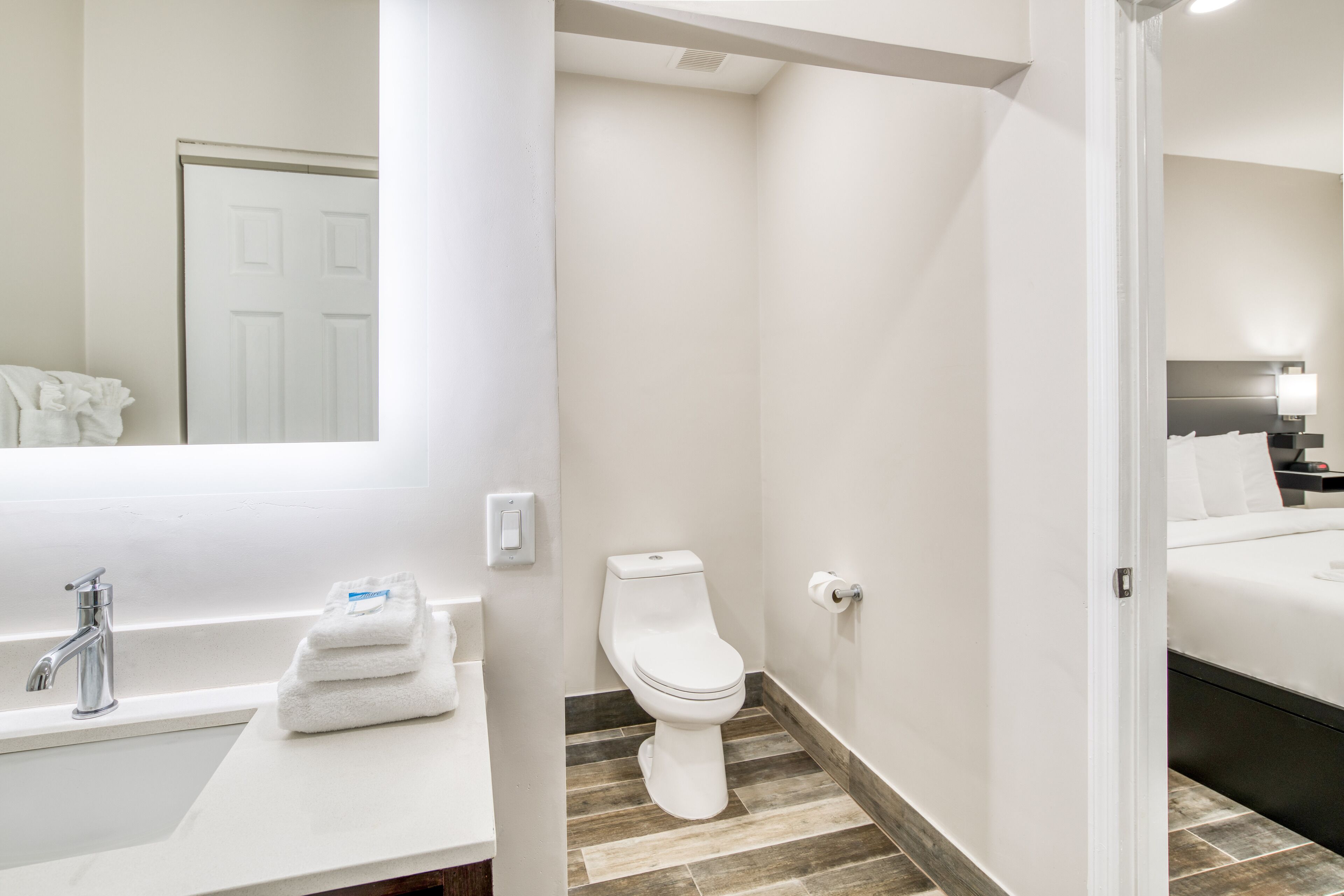 A bathroom with a white sink, a toilet, and a mirror.