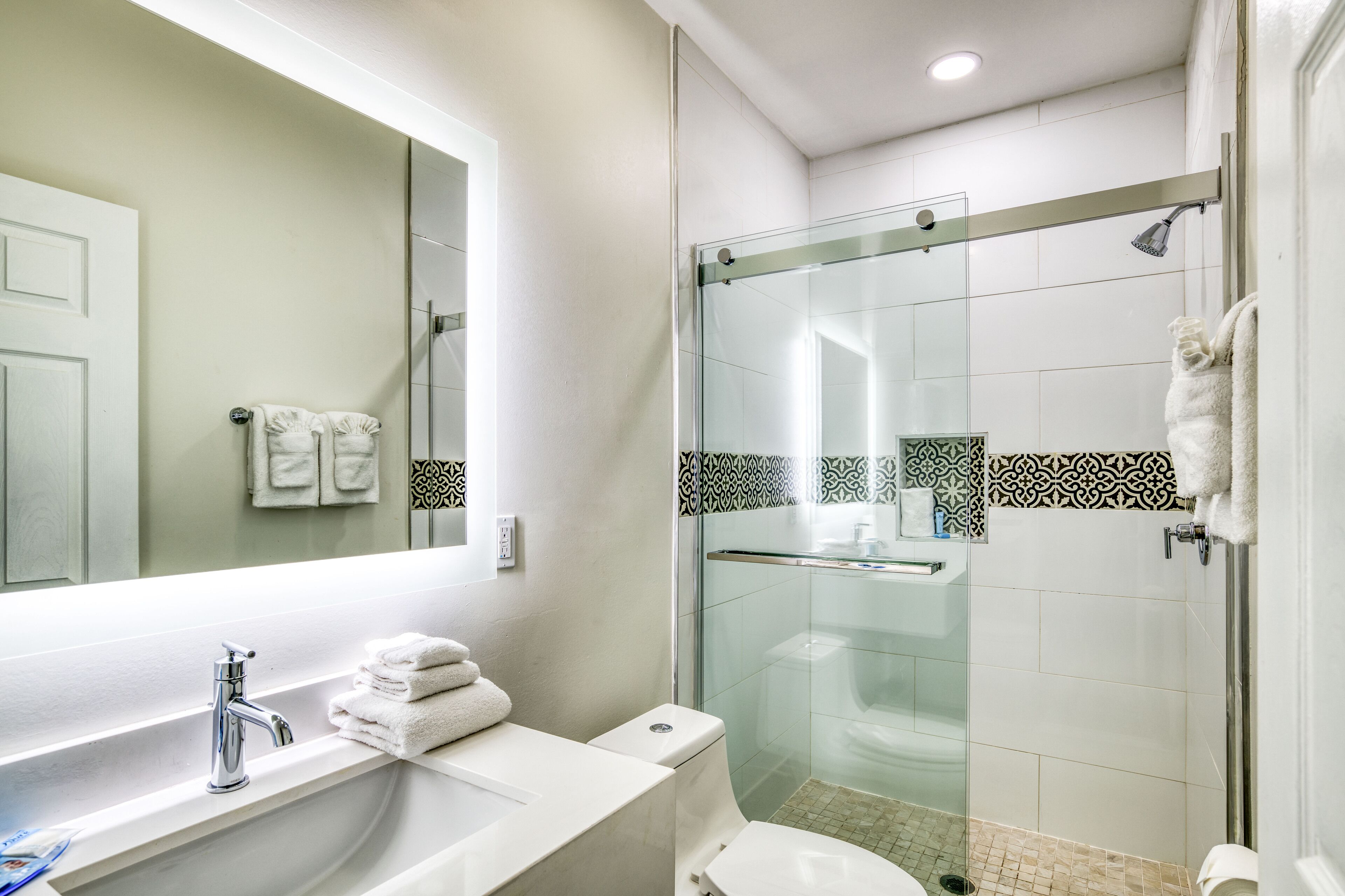 Een moderne badkamer met een douchecabine van glas, een wit wastafelmeubel en een toilet.