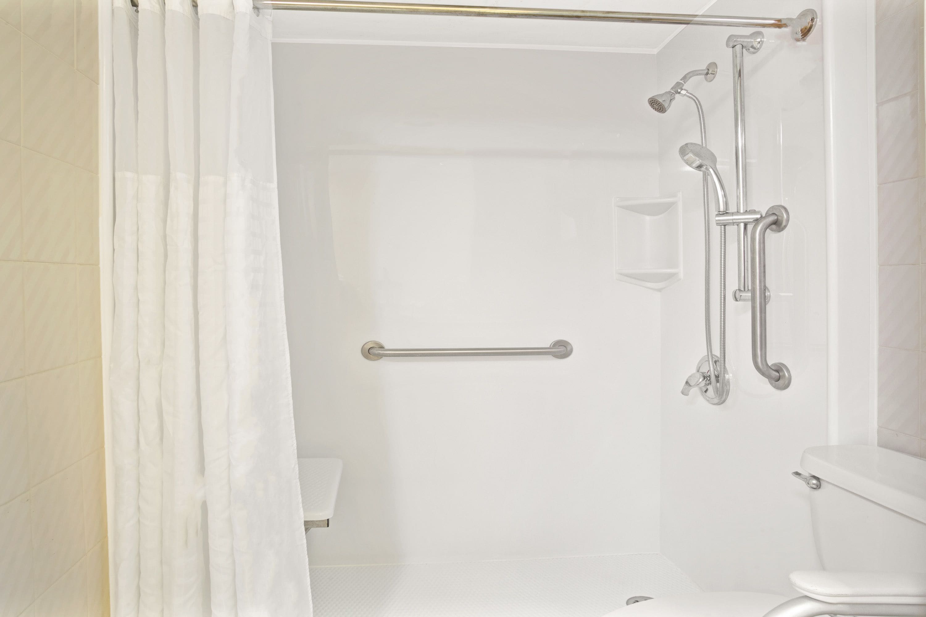 Ein Badezimmer mit Dusche, Haltegriff und Toilette.
