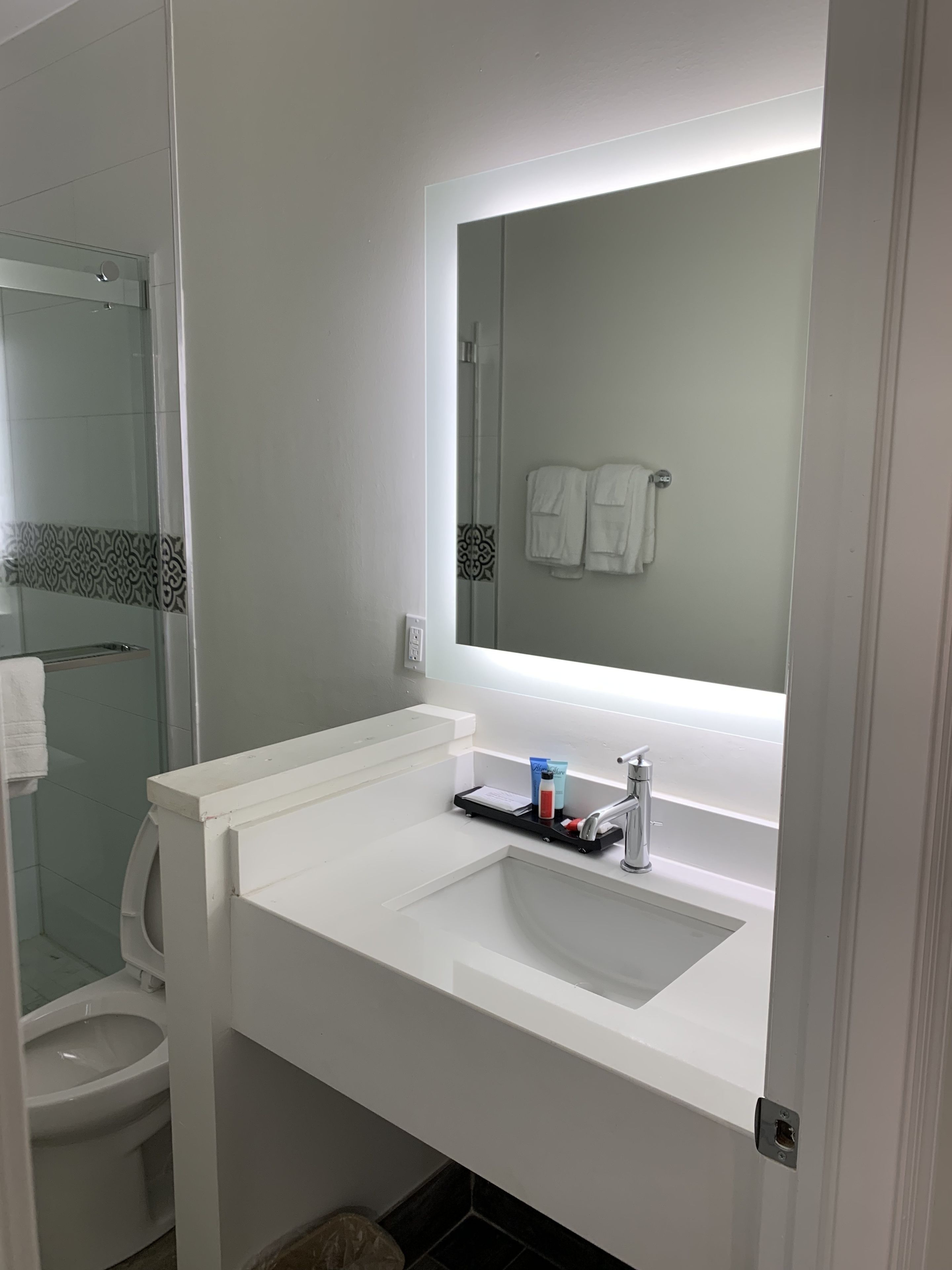 Un bany modern amb un lavabo blanc, un mirall i un vàter.