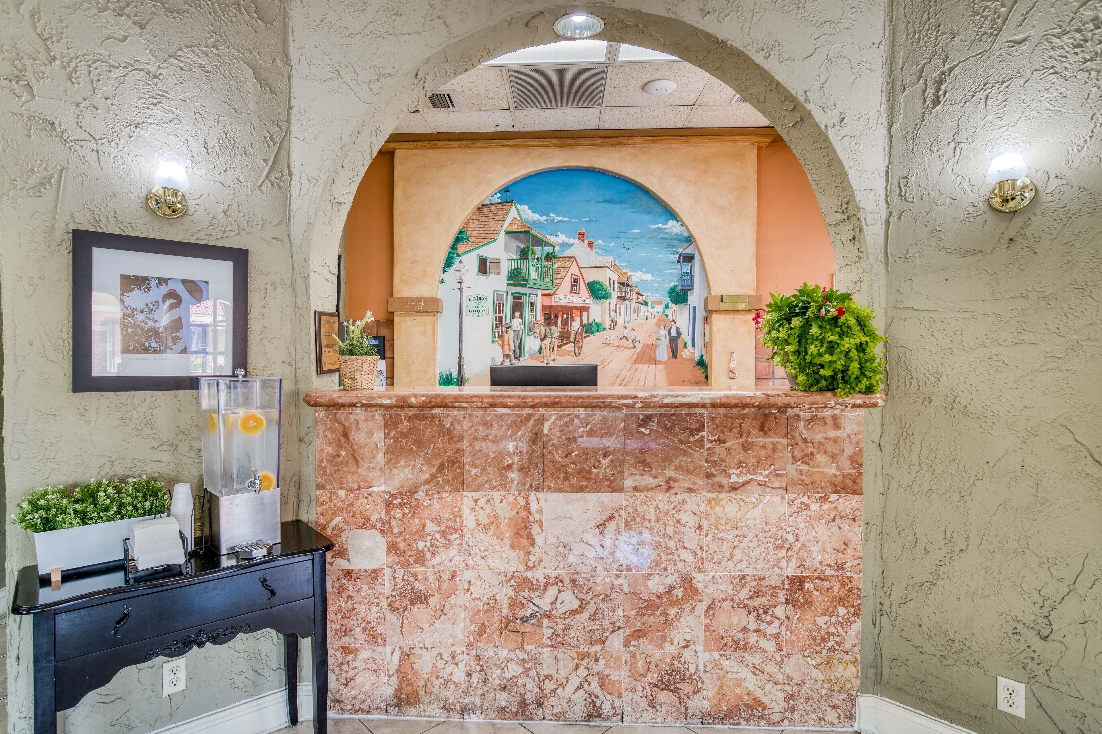 A reception area with a marble counter, a framed picture, and a mural of a street scene.