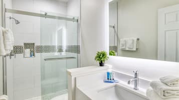 A modern bathroom with a glass-enclosed shower, a white sink with a mirror, and a toilet.