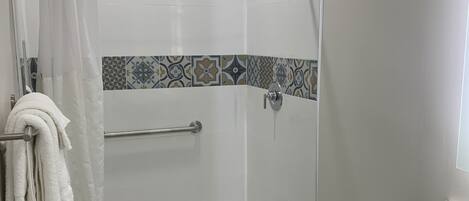 Een moderne badkamer met een douche, toilet en wastafel.