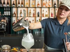 A bartender pouring a drink into a glass.