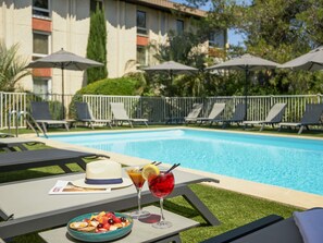 Una piscina al aire libre, sillones reclinables de piscina