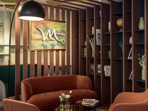 Een modern interieur met een wand van houten latten, een groot kunstwerk in een lijst, een bruine bank en een wereldbol op een plank.
