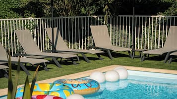 Una piscina al aire libre, sillones reclinables de piscina