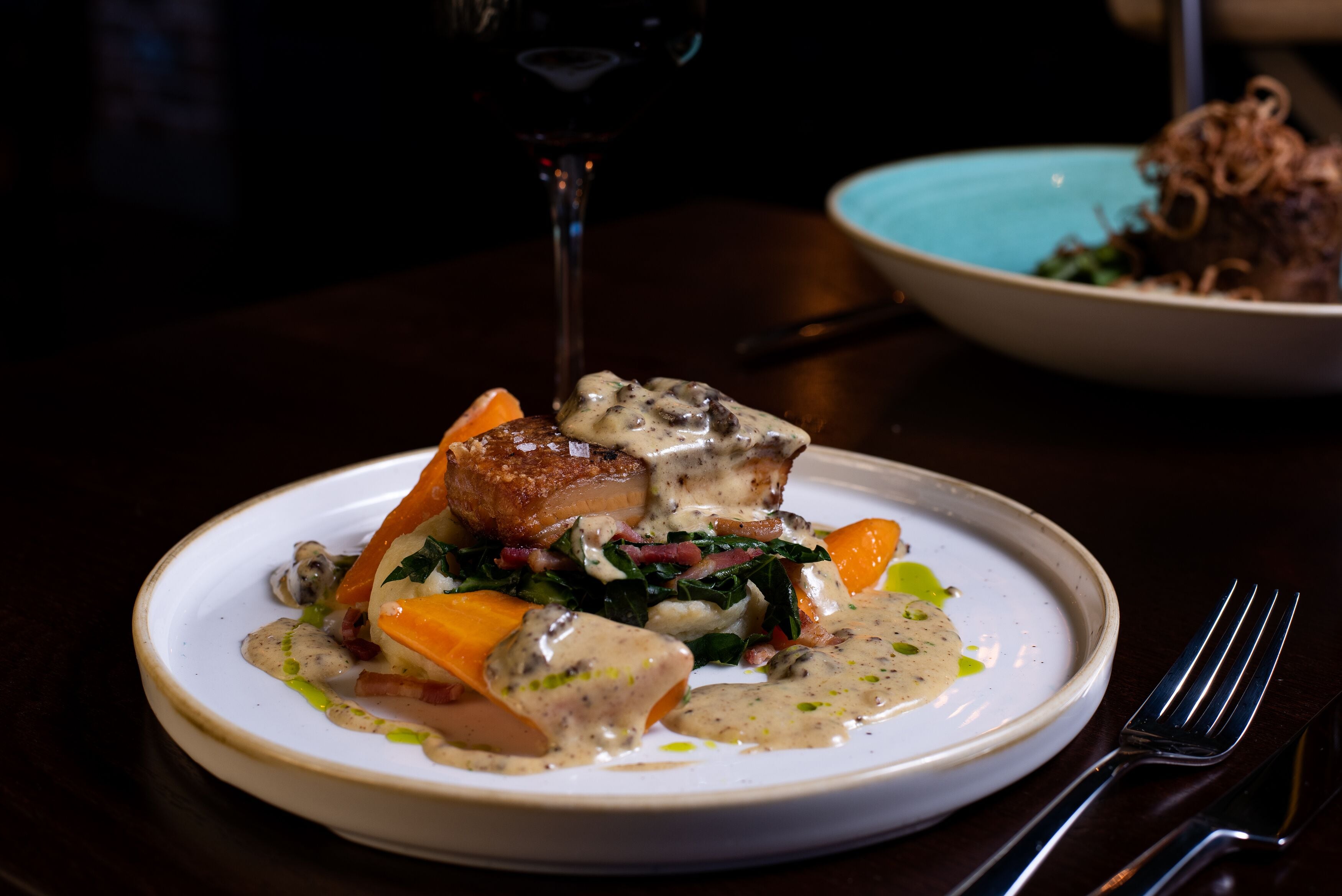 A plate of food with a glass of red wine on a table.