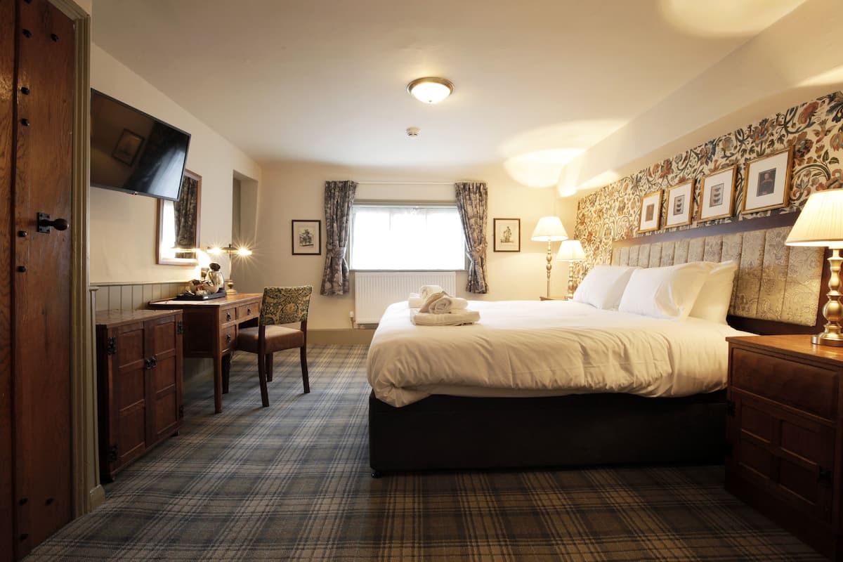 A hotel room with a bed, a desk, a chair, a television, and a window with curtains.