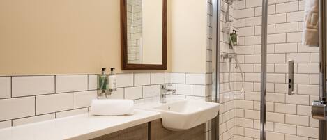 A bathroom with a white sink, a mirror, and a glass-enclosed shower.