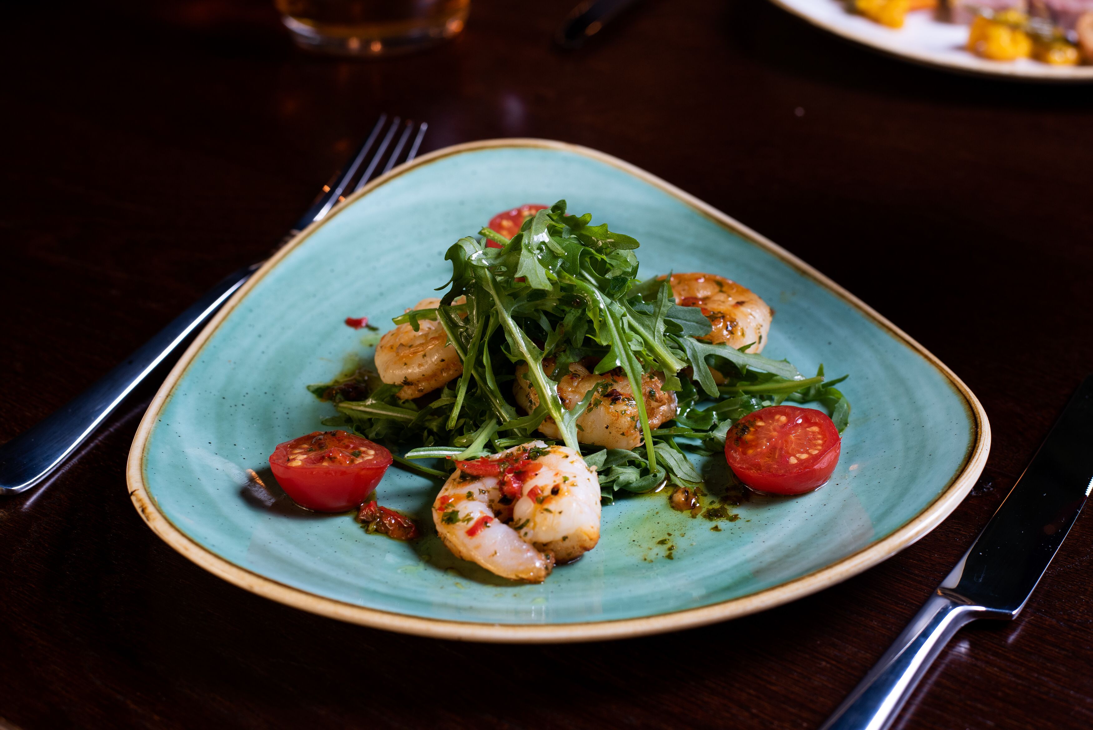A plate of food with shrimp and greens on a ceramic plate.