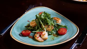 A plate of food with shrimp and greens on a ceramic plate.