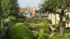 Una casa de estilo Tudor tradicional con un jardín cuidado, muros de piedra y césped.