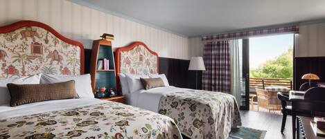 A hotel room with two beds, a desk, and a balcony with a view.