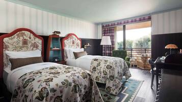 Habitación de hotel con dos camas, un escritorio, una silla y vistas al exterior.