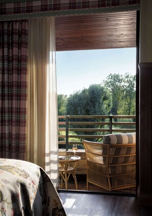 A room with a bed, a wicker chair, a small table, and a view of the outdoors. - Graduate by Hilton Cambridge (Cambridge)