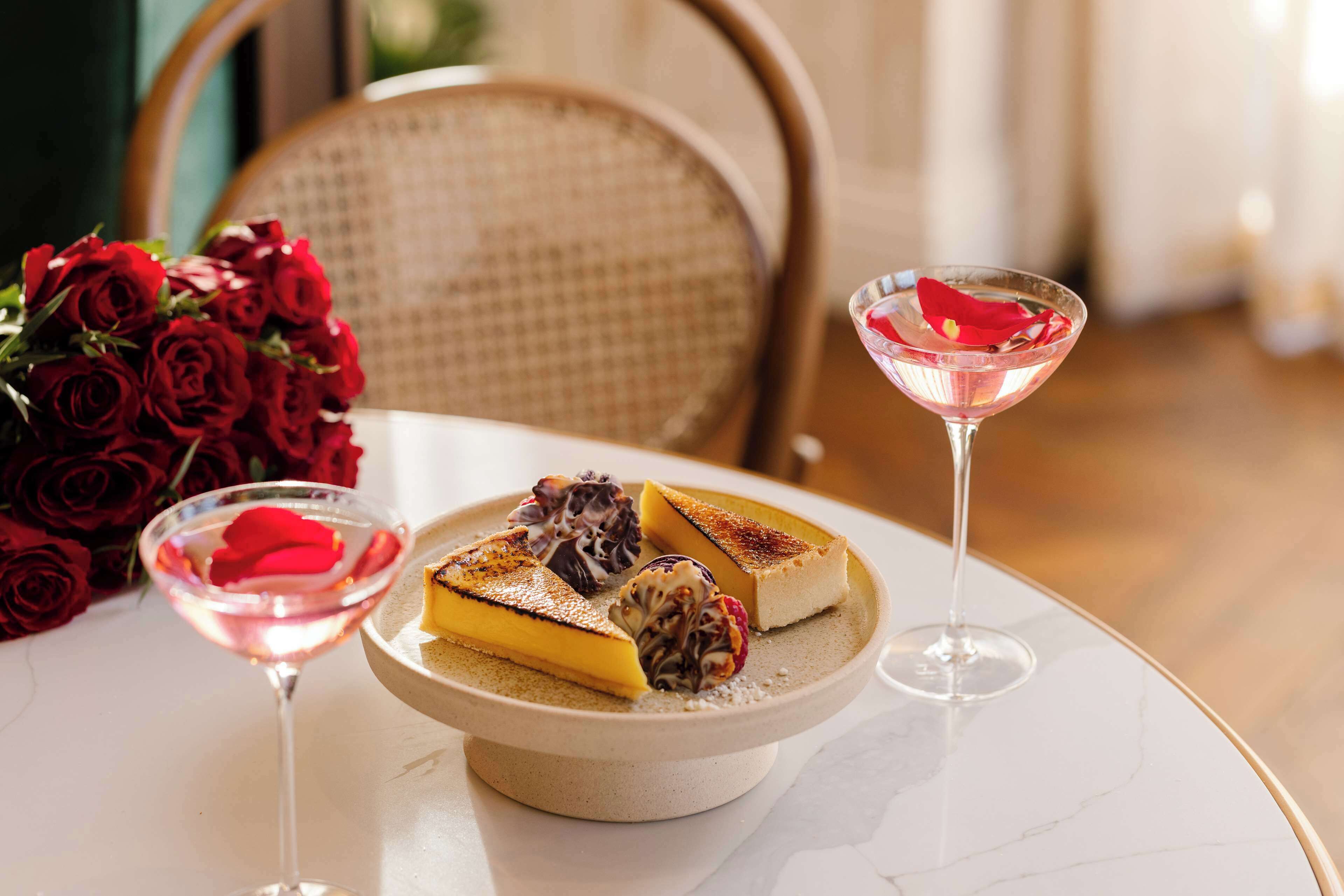 A dessert plate with a slice of cake and a martini glass on a marble table.