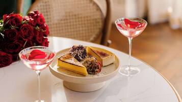 A dessert plate with a slice of cake and a martini glass on a marble table.