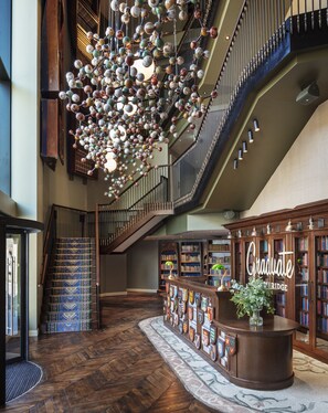 A spacious lobby with a grand staircase, a decorative ceiling, and a reception desk with a 'Graduate' sign. - Graduate by Hilton Cambridge (Cambridge)