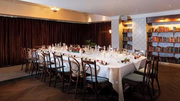 Ein formeller Speisesaal mit einem runden Tisch, der für eine Mahlzeit gedeckt ist, umgeben von Holzsesseln.