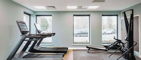A gym with treadmills, a stationary bike, and a rowing machine.
