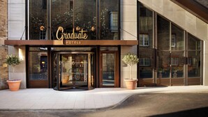 A modern hotel with large glass windows, a prominent 'Graduate Hotels' sign, and a brick facade.