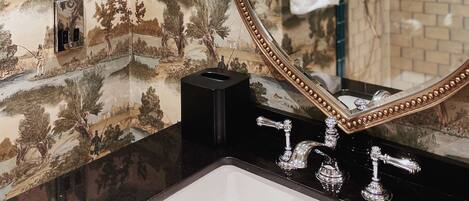 A bathroom with a large mirror, a sink, and a shower.