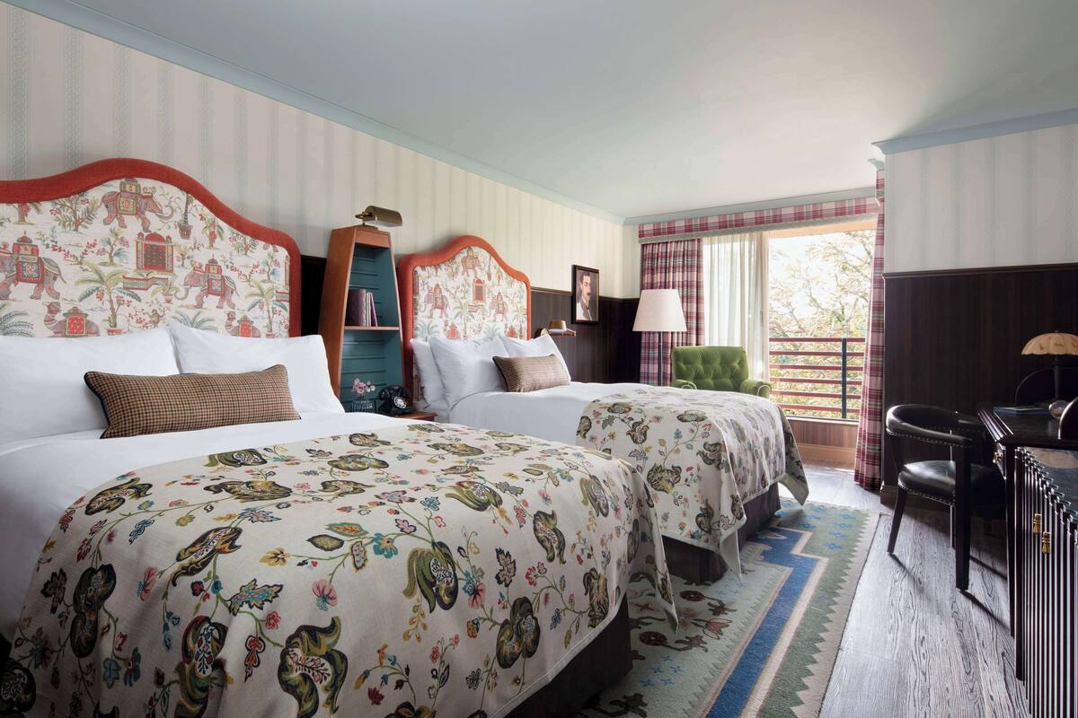 A hotel room with two beds, a desk, and a chair.