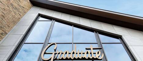 A hotel sign with the name "Graduate Hotels" above a large window.