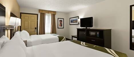 A hotel room with two beds, a television, a desk, and a door.