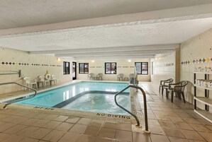 Piscina interior con un cartel de 'NO DIVING', rodeada de sillas y estanterías con toallas.