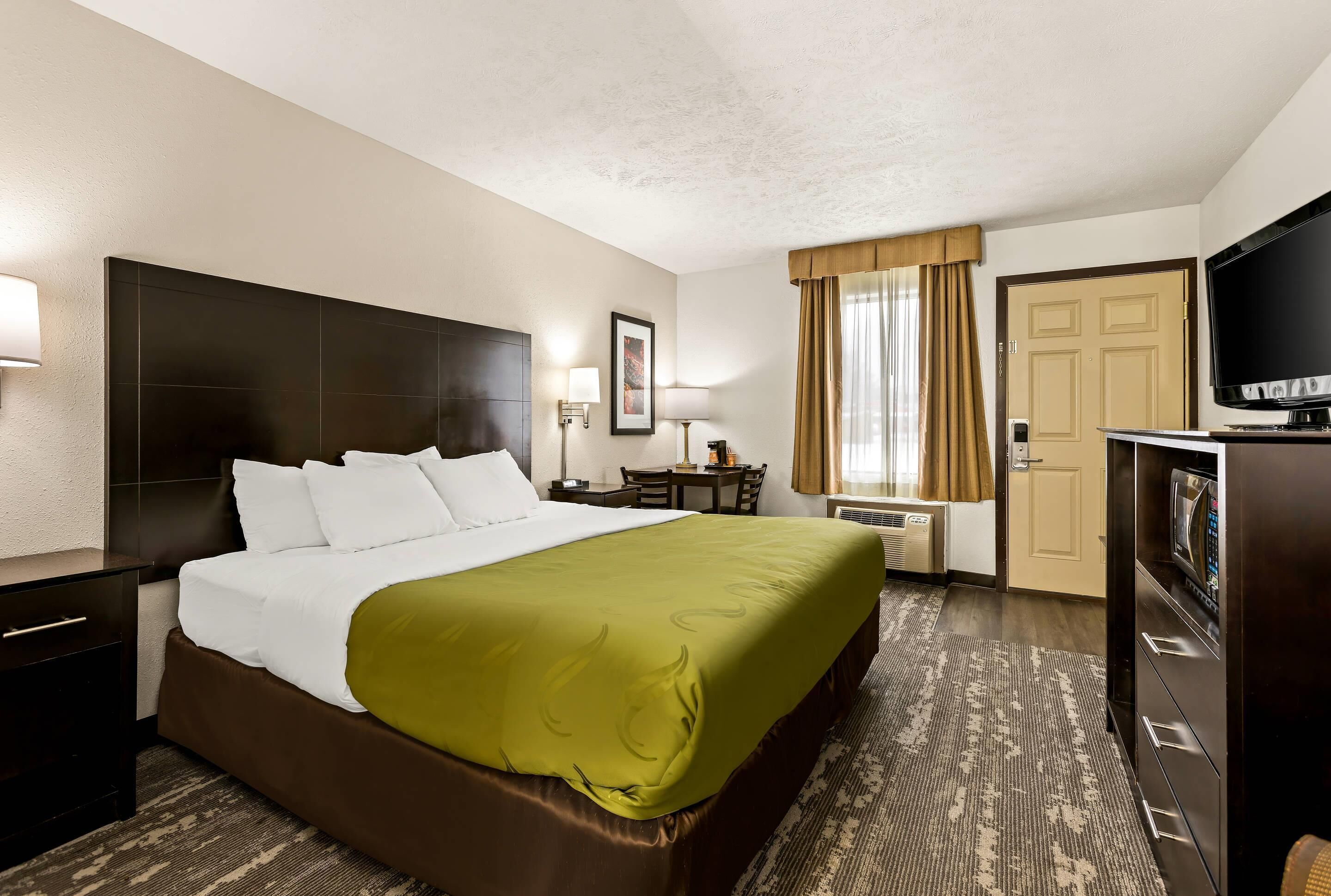 Une chambre d’hôtel avec un grand lit, une télévision, un bureau et une chaise.