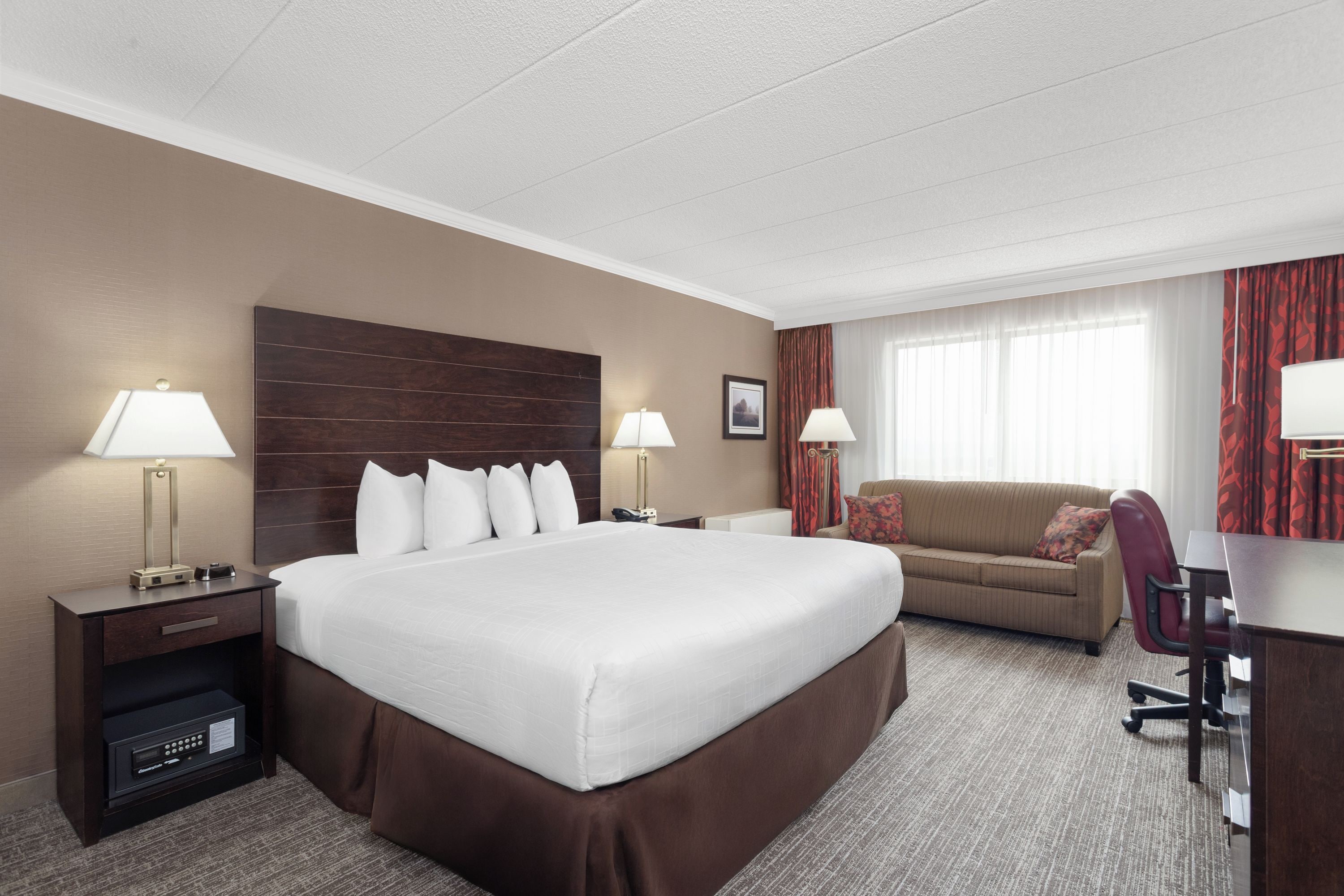 Ein Hotelzimmer mit einem großen Bett, einem Schreibtisch, einem Sessel, einer Couch und zwei Lampen.