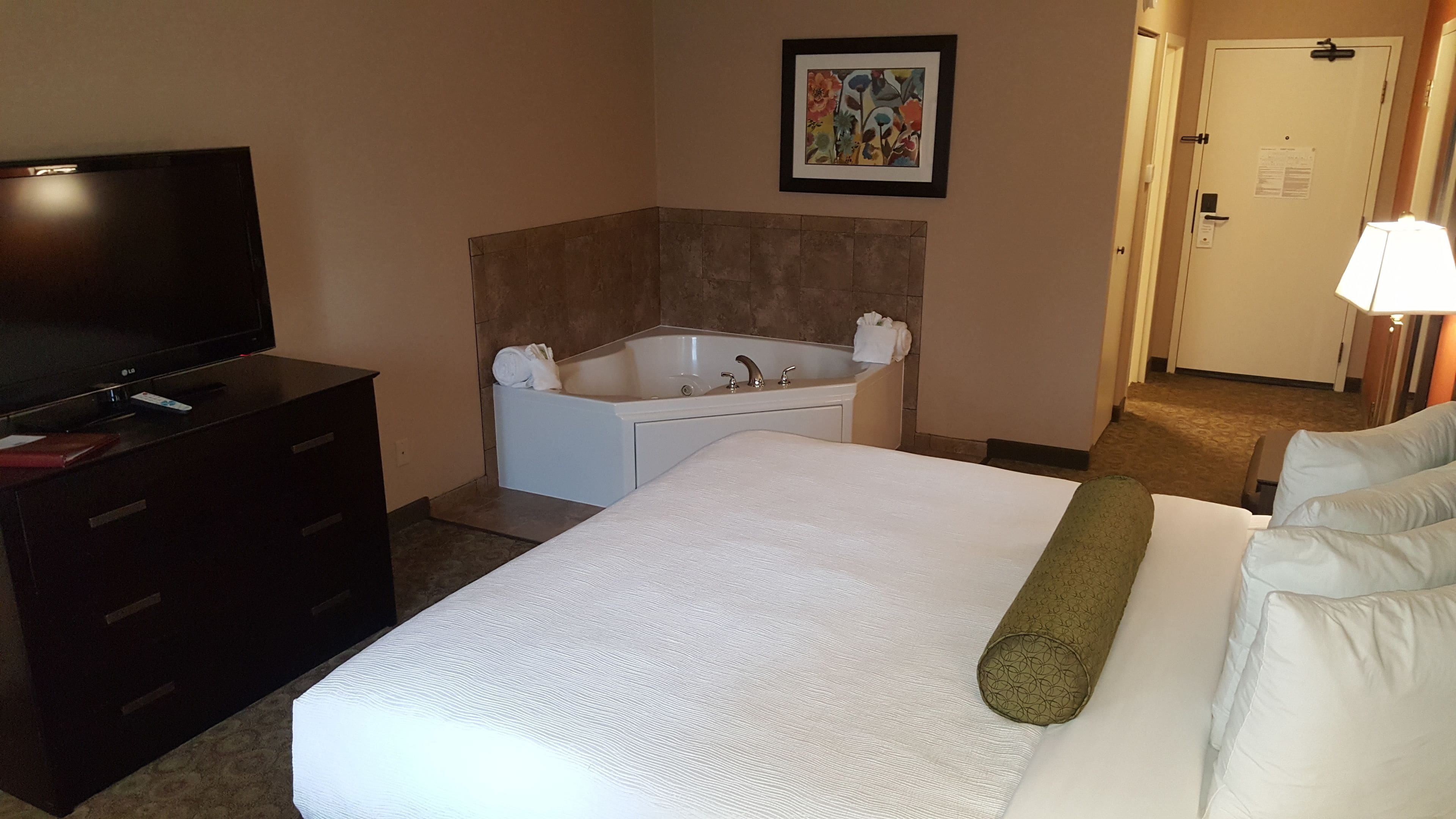 Une chambre d’hôtel avec un lit, une télévision, une baignoire et une porte.