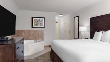 Habitación de hotel con una cama grande, un televisor de pantalla plana, una bañera y una obra de arte enmarcada en la pared.