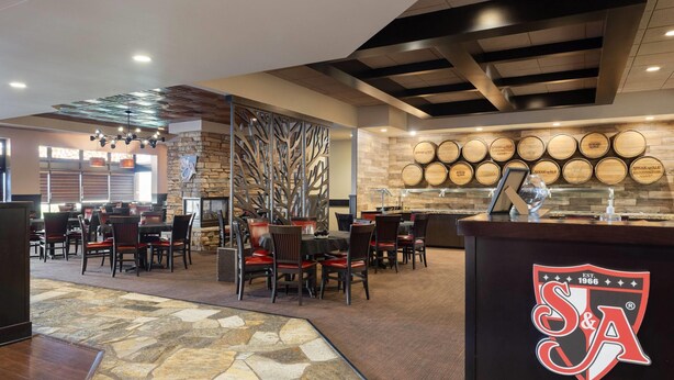 A restaurant with a stone floor, wooden barrels on the wall, and a logo on the counter. - Wyndham Minneapolis South/Burnsville (Burnsville)