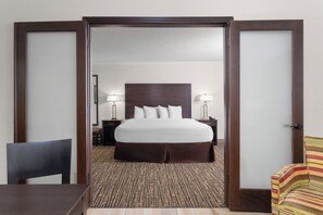 A hotel room with a bed, bedside tables, a chair, and a striped armchair. -  Wyndham Minneapolis South/Burnsville (Burnsville)