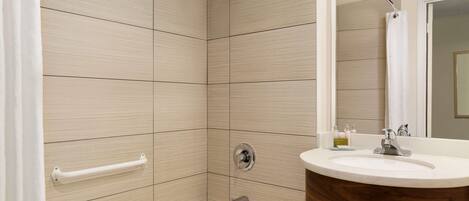 A modern bathroom with a bathtub, a vanity with a wooden basin, and a shower area with a glass door.